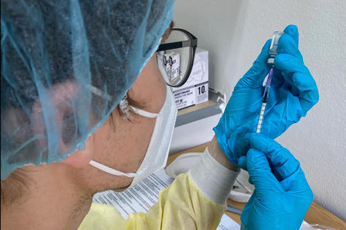 Sorgfältig zieht ein Mitarbeiter der Impfstelle eine Spritze auf.