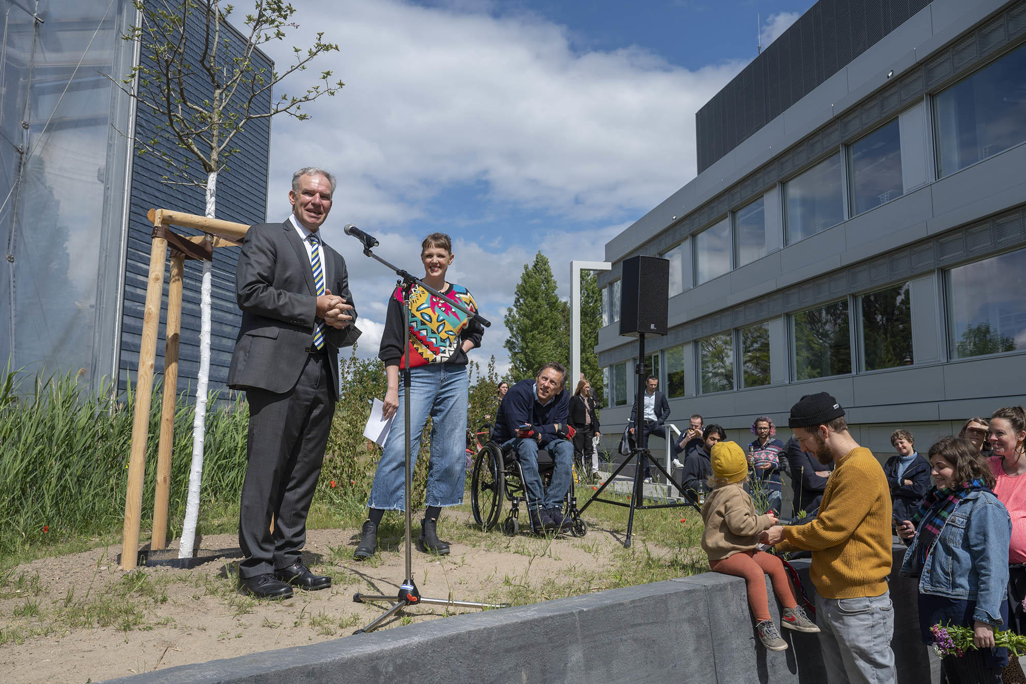 Rainer Haag steht vor einem Mikrofon vor der Schaukelinstallation, Katja Maria Vogt steht rechts neben ihm.