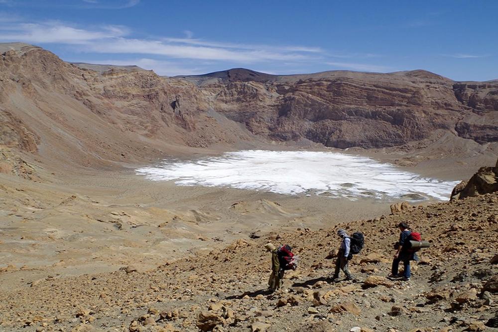 Descent into the Era Kohor subcrater within the summit caldera of Emi Koussi, the highest mountain in the Sahara, at 3,415 meters. Whitish sediments can be seen on the crater floor – salt crusts from when the lake dried up.