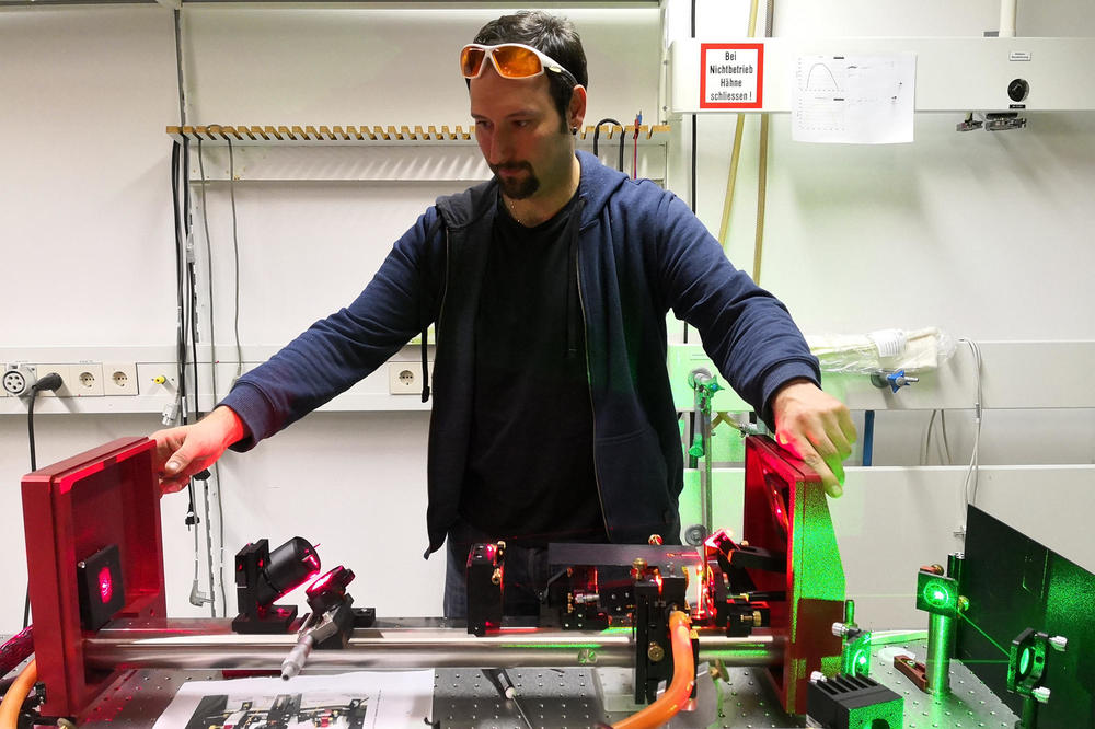 Postdoc Patryk Kusch – shown here in front of the Freie Universität measuring laser – did research at the Universidade Federal de Minas Gerais in Brazil thanks to a Research Alumni Program fellowship.