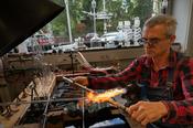 Dirk Busold wickelt eine Glasröhre um eine Metallstange. So entsteht eine spiralförmige Glaswendel, die als Kühlschlange in Laborapparaturen eingesetzt wird.