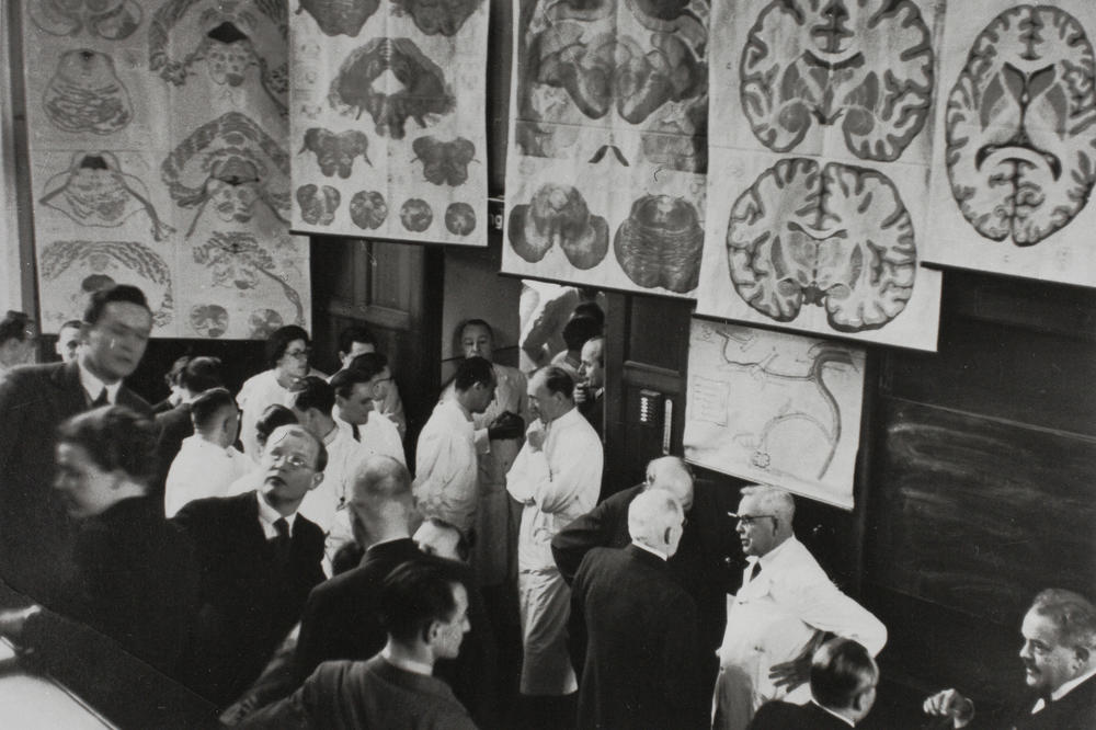 Der Leiter der damaligen Psychiatrischen- und Nervenklinik Karl Bonhoeffer (re. im weißen Kittel) bei seiner Abschiedsvorlesung 1938 im Gespräch mit dem Chirurgen F. Sauerbruch (re. von ihm) und dem Gynäkologen W. Stoeckel (li. von ihm).