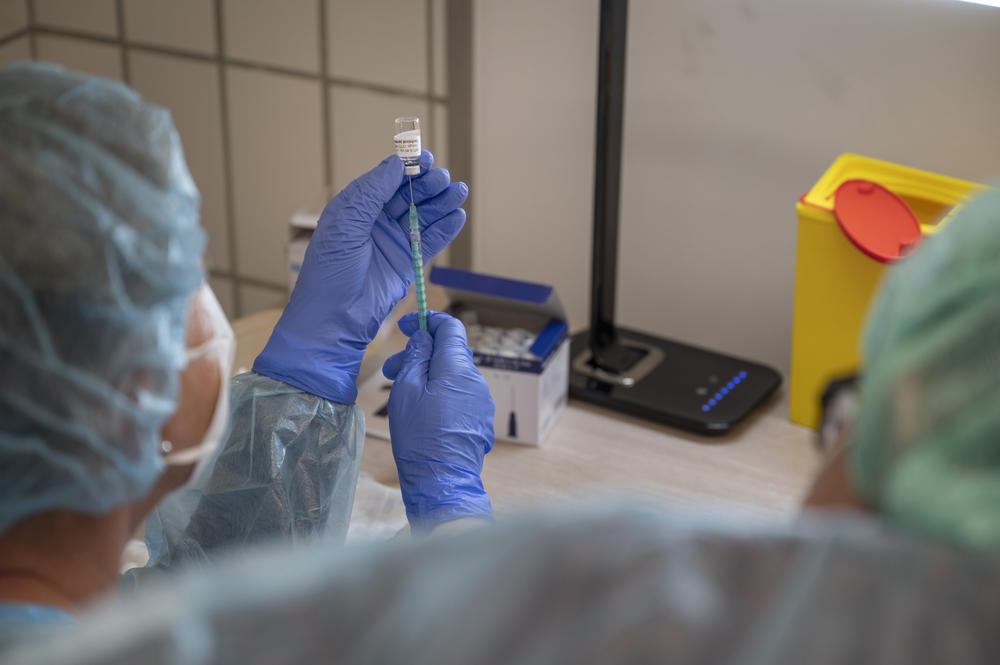 Eine Person zieht einen Impfstoff gegen das Coronavirus in eine Spritze auf.